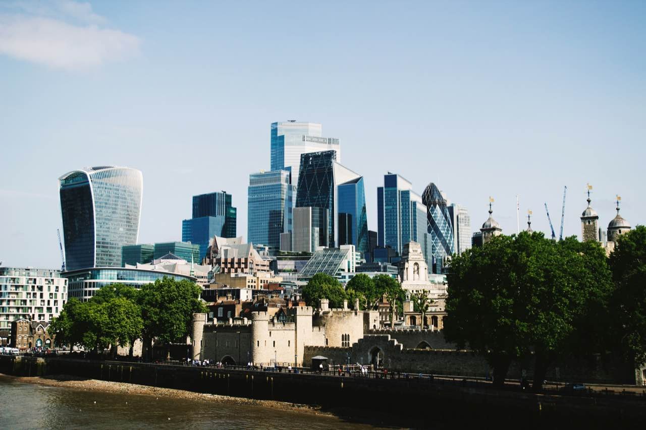 The towers of the City of London rising behind the Tower of London, seen across the Thames