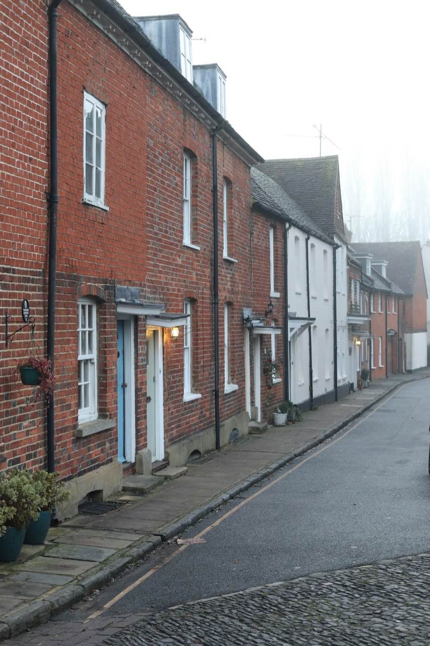 A row of red-brick and white terraced cottages along a misty lane